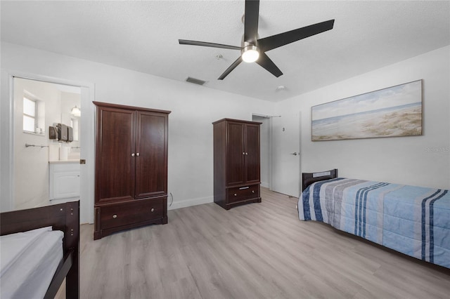 bedroom with light wood finished floors, a ceiling fan, visible vents, and a textured ceiling