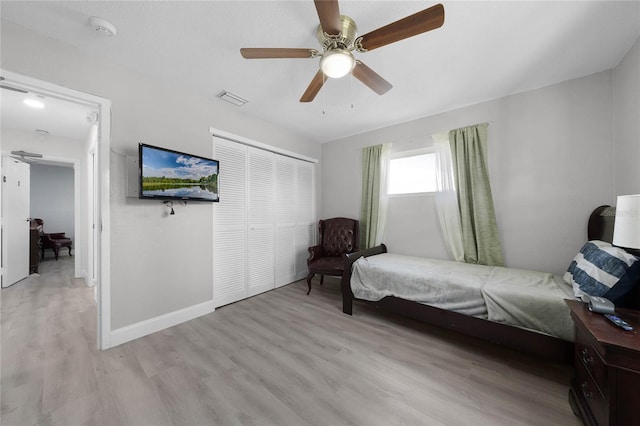 bedroom with light wood finished floors, a closet, visible vents, ceiling fan, and baseboards