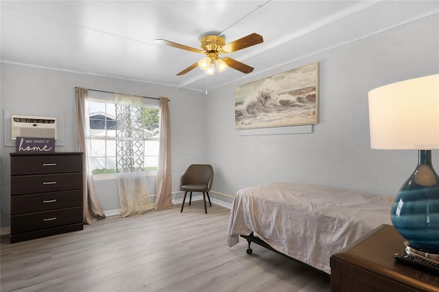 bedroom with light wood-style floors, a ceiling fan, baseboards, and a wall mounted AC