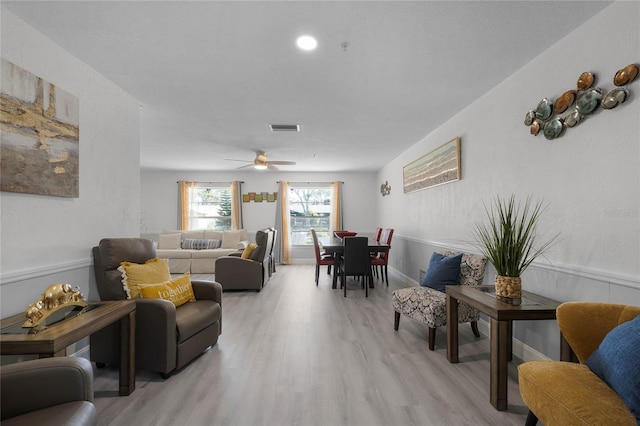 living room featuring light wood finished floors, visible vents, and wainscoting