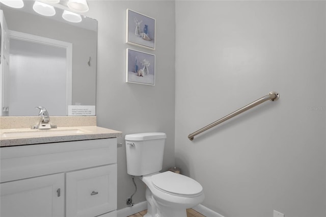 bathroom with baseboards, vanity, and toilet