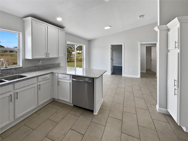 kitchen featuring a peninsula, stainless steel dishwasher, a sink, and white cabinetry