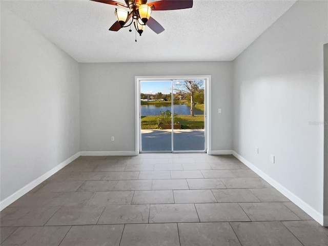 spare room featuring a textured ceiling, a water view, a ceiling fan, and baseboards