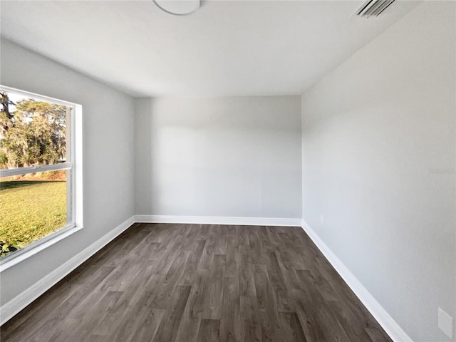 empty room featuring baseboards, visible vents, and dark wood finished floors