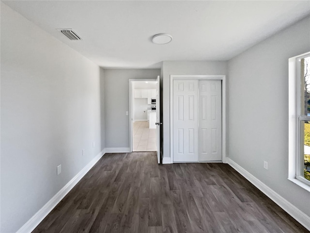 unfurnished bedroom with baseboards, multiple windows, and visible vents