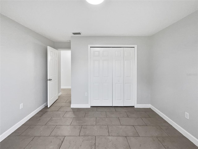 unfurnished bedroom with baseboards, visible vents, and a closet