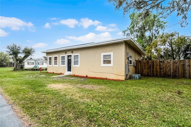 view of front of house with a front yard, fence, cooling unit, and stucco siding