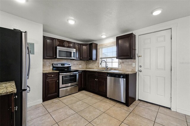 1622 Dolphin Dr, Saint Cloud, FL 34771 - kitchen with dark brown cabinetry, tasteful backsplash, light tile patterned floors, appliances with stainless steel finishes, and a sink