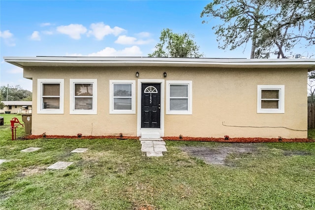 view of front of property featuring stucco siding and a front yard