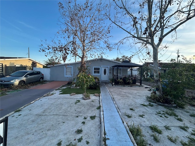 ranch-style home with driveway, fence, a gazebo, and stucco siding