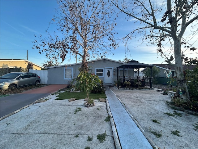 view of front of property with a gazebo, fence, driveway, and stucco siding