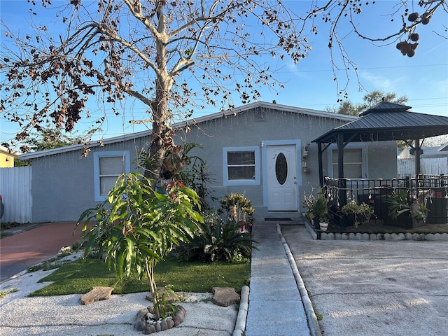 view of front of property featuring stucco siding, fence, and a gazebo