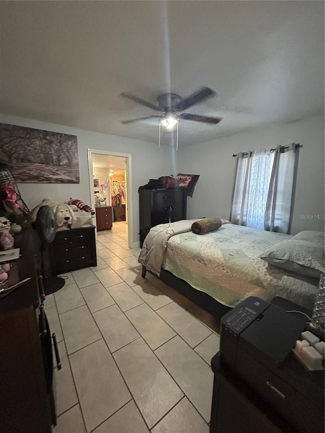 bedroom featuring ceiling fan, a spacious closet, and light tile patterned floors