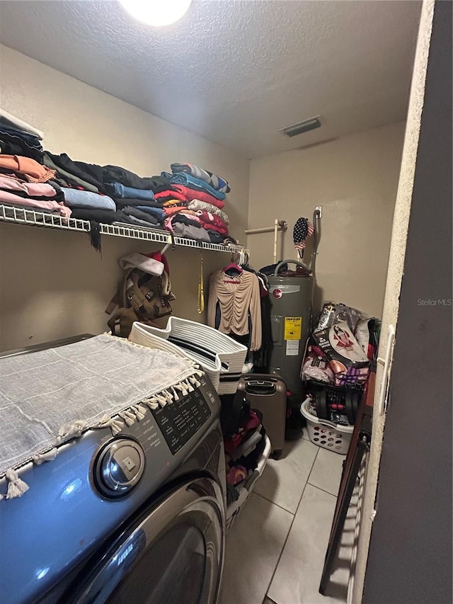 interior space featuring light tile patterned floors, visible vents, washer / clothes dryer, and electric water heater