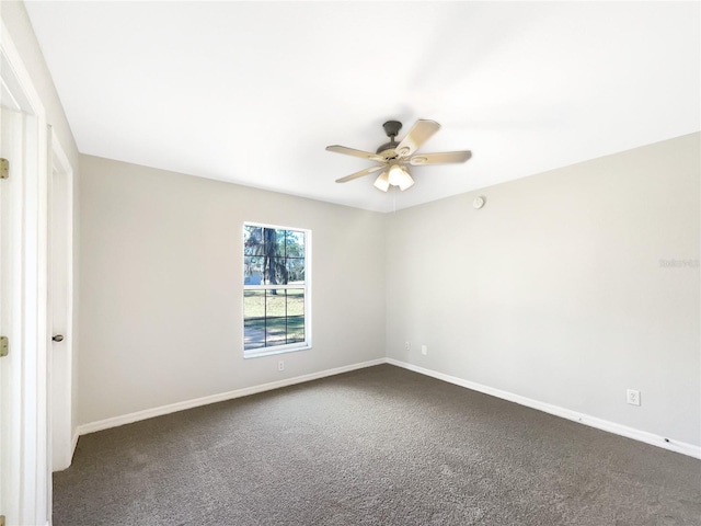 empty room featuring a ceiling fan, dark colored carpet, and baseboards