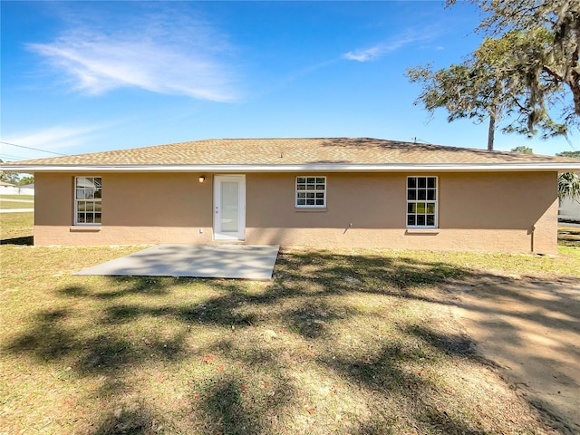 rear view of house featuring a patio, a lawn, and stucco siding