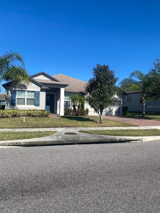 view of front of property with a front lawn, driveway, an attached garage, and stucco siding