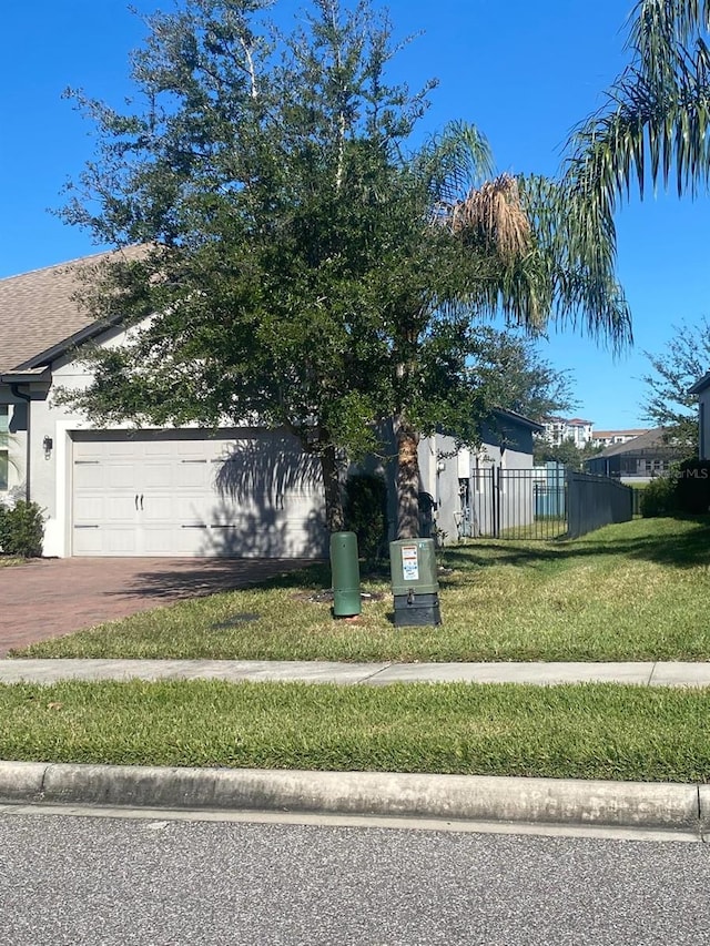 view of home's exterior featuring a garage, fence, decorative driveway, and a yard