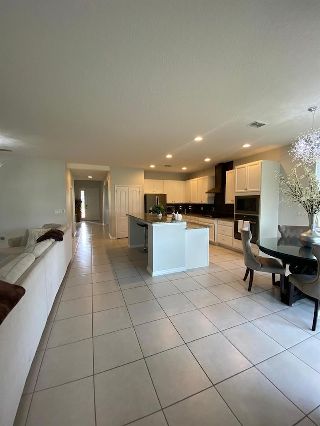 kitchen with stainless steel appliances, visible vents, open floor plan, white cabinetry, and wall chimney range hood