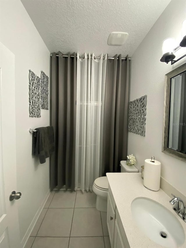 full bathroom with baseboards, toilet, tile patterned flooring, a textured ceiling, and vanity