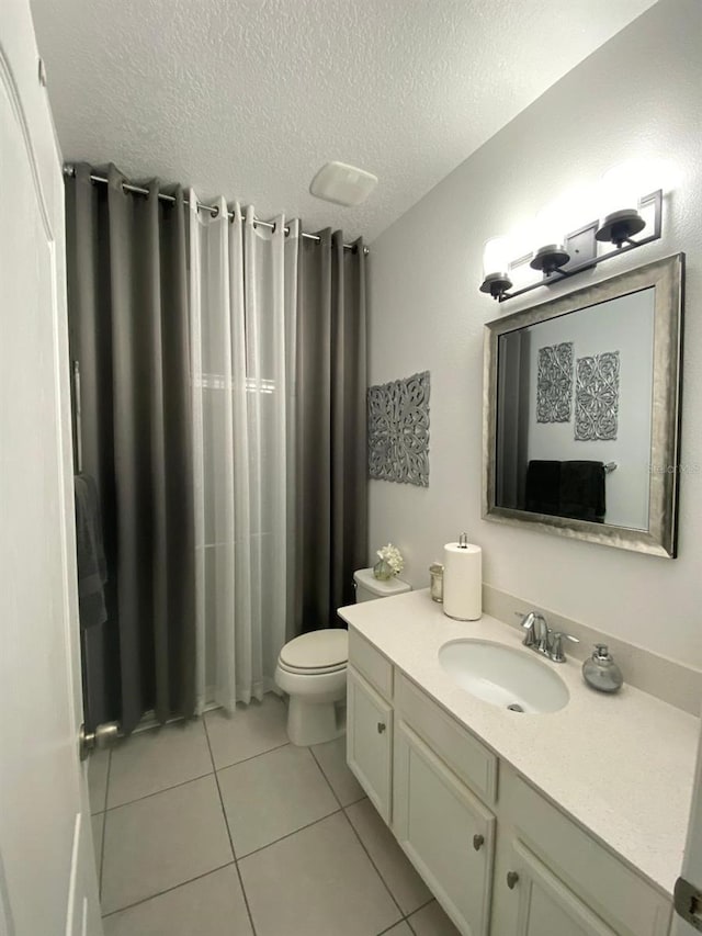 full bath with toilet, tile patterned flooring, a textured ceiling, and vanity