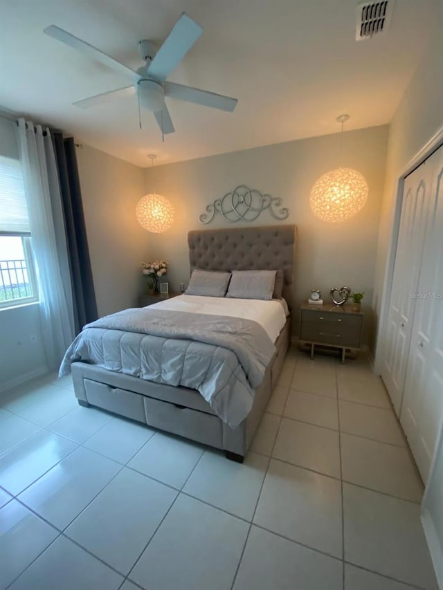 bedroom with a closet, visible vents, ceiling fan, and light tile patterned floors