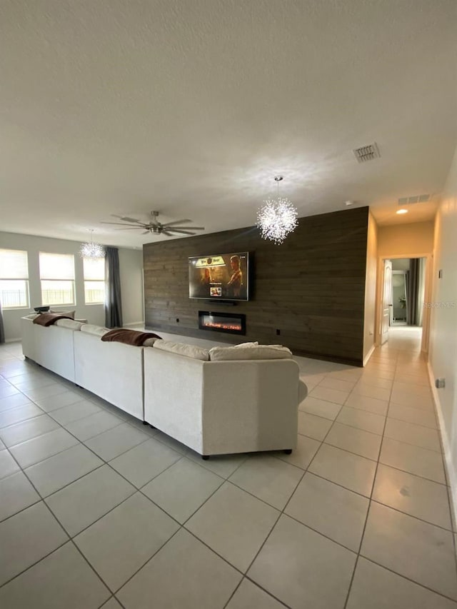 unfurnished living room with light tile patterned floors, wooden walls, visible vents, and a glass covered fireplace