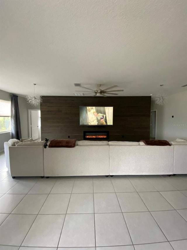 unfurnished living room featuring a warm lit fireplace, an accent wall, light tile patterned floors, and wooden walls