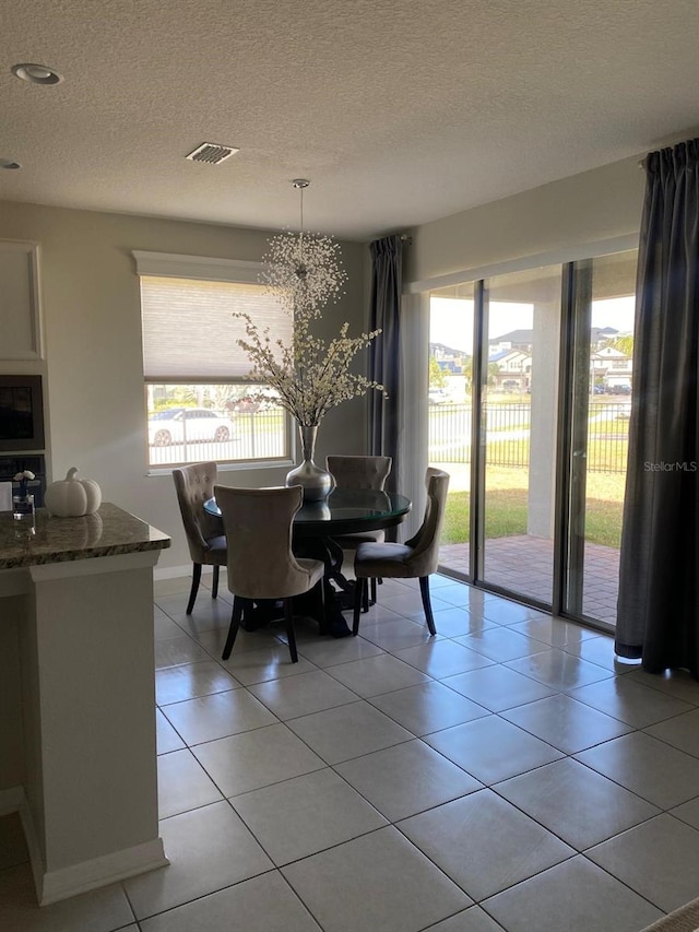 dining space with visible vents, a textured ceiling, and light tile patterned flooring