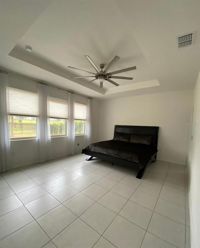 bedroom with ceiling fan, light tile patterned flooring, a raised ceiling, and visible vents