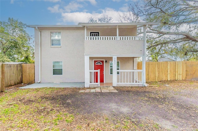 view of front facade featuring a fenced backyard, a balcony, and stucco siding