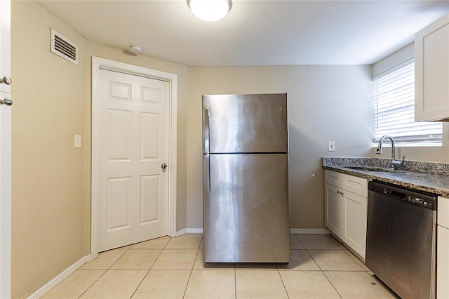 kitchen with light tile patterned floors, visible vents, appliances with stainless steel finishes, a sink, and dark stone countertops