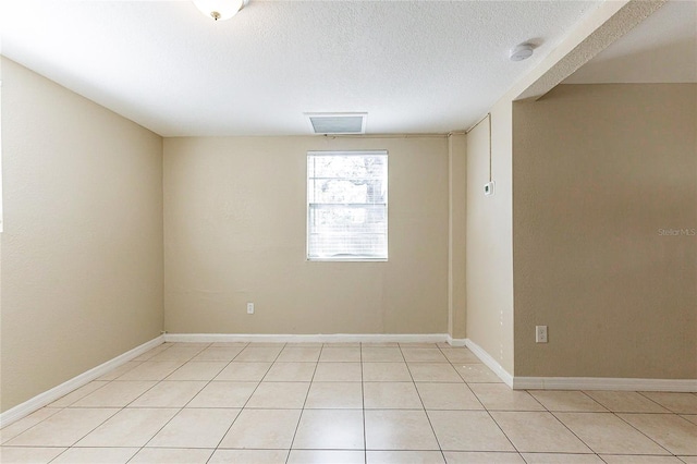 unfurnished room featuring a textured ceiling, baseboards, and light tile patterned floors