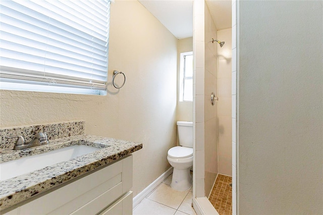 bathroom featuring baseboards, toilet, tile patterned floors, a tile shower, and vanity