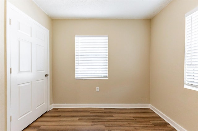 empty room featuring dark wood-style flooring, a healthy amount of sunlight, and baseboards