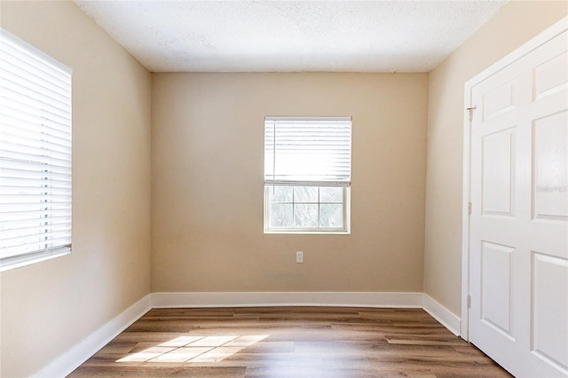 empty room featuring baseboards, a wealth of natural light, and wood finished floors