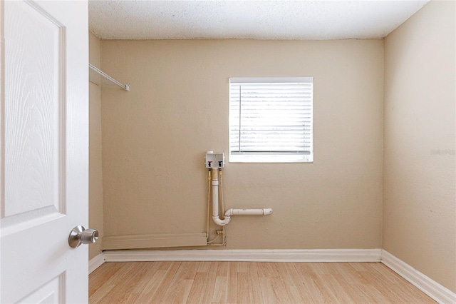 washroom featuring a textured ceiling, laundry area, wood finished floors, and baseboards