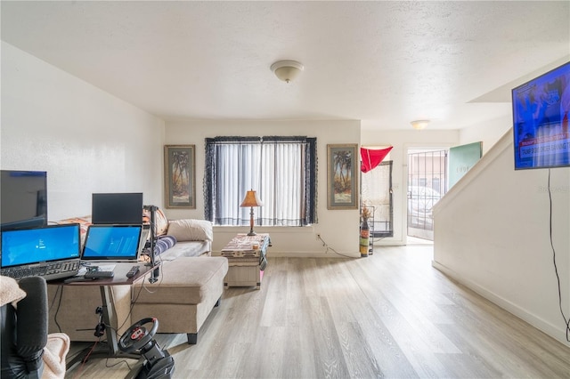 living room featuring a textured ceiling, light wood finished floors, and baseboards