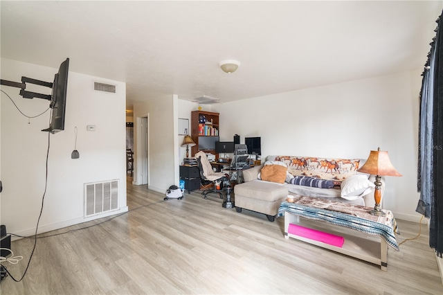 living area featuring light wood-style flooring, visible vents, and baseboards