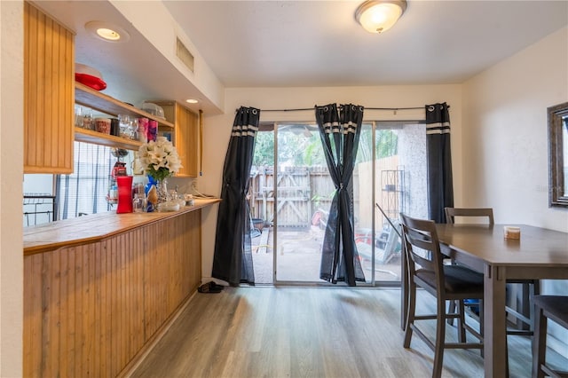 dining space featuring visible vents, light wood-style flooring, and a dry bar