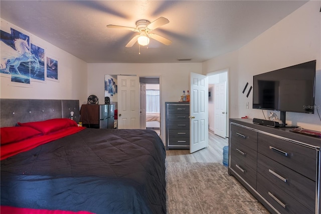 bedroom featuring light wood-type flooring, visible vents, and a ceiling fan