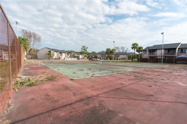 view of tennis court with a residential view and fence