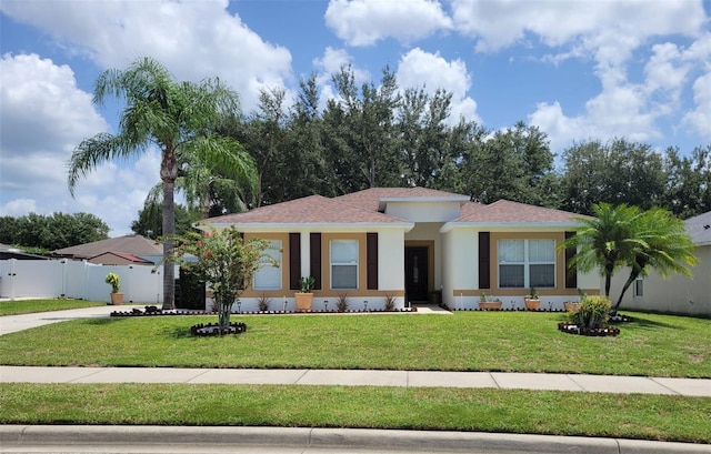 view of front of property featuring a shingled roof, a front lawn, fence, stucco siding, and driveway