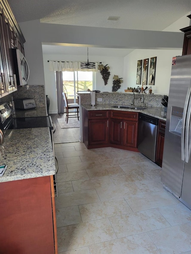 kitchen featuring a sink, appliances with stainless steel finishes, a peninsula, light stone countertops, and dark brown cabinets