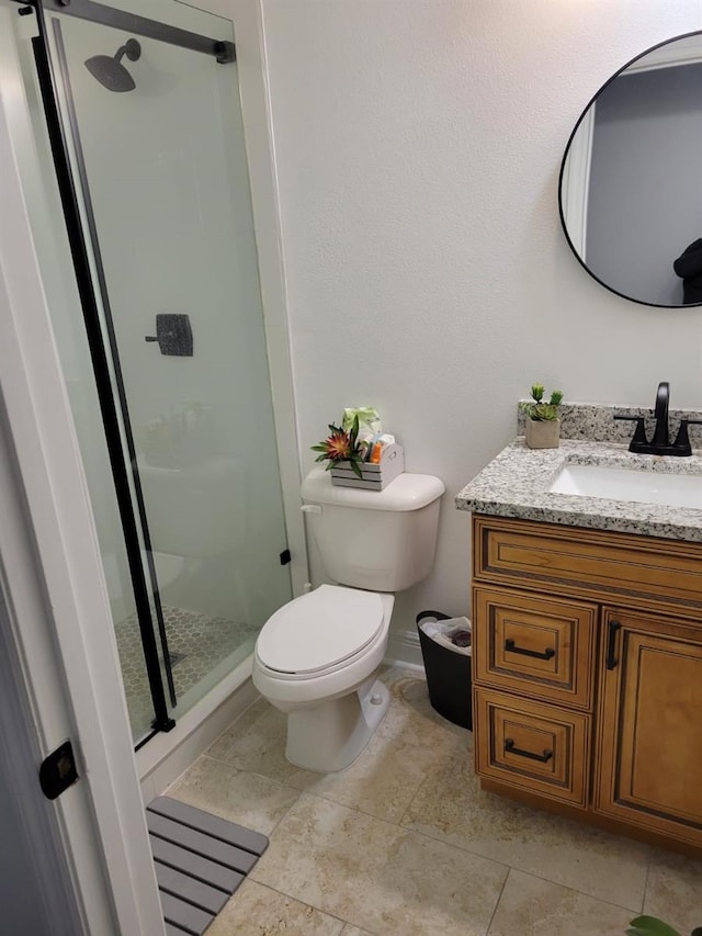 full bath with tile patterned floors, toilet, a shower stall, baseboards, and vanity