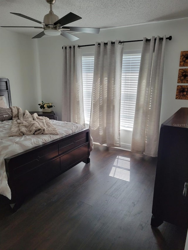 bedroom featuring dark wood-type flooring, ceiling fan, and a textured ceiling