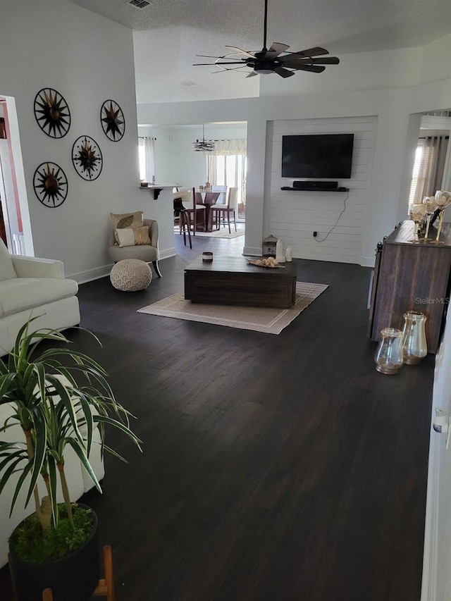 living area with visible vents, baseboards, a textured ceiling, a ceiling fan, and dark wood-style flooring