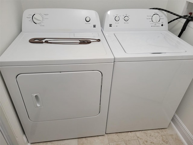 washroom with laundry area, washing machine and dryer, and baseboards