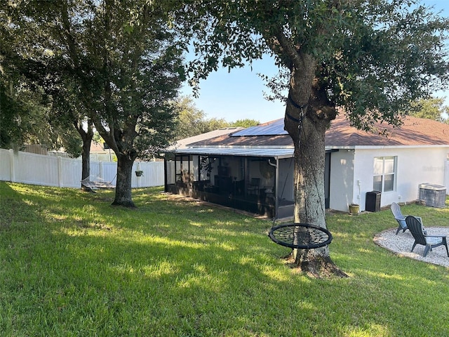 view of yard featuring central air condition unit, fence, an outdoor fire pit, and a sunroom