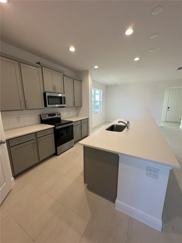 kitchen with tasteful backsplash, recessed lighting, gray cabinets, appliances with stainless steel finishes, and a sink